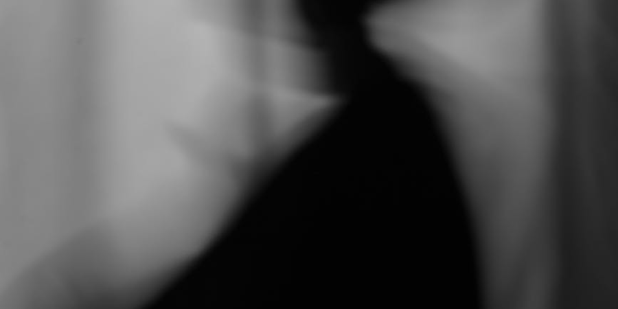 Abstract black-and-white silhouette of a person with motion blur against a curtain background.