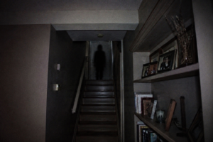 Dark eerie staircase with a shadowy figure at the top, creating a spooky mood.