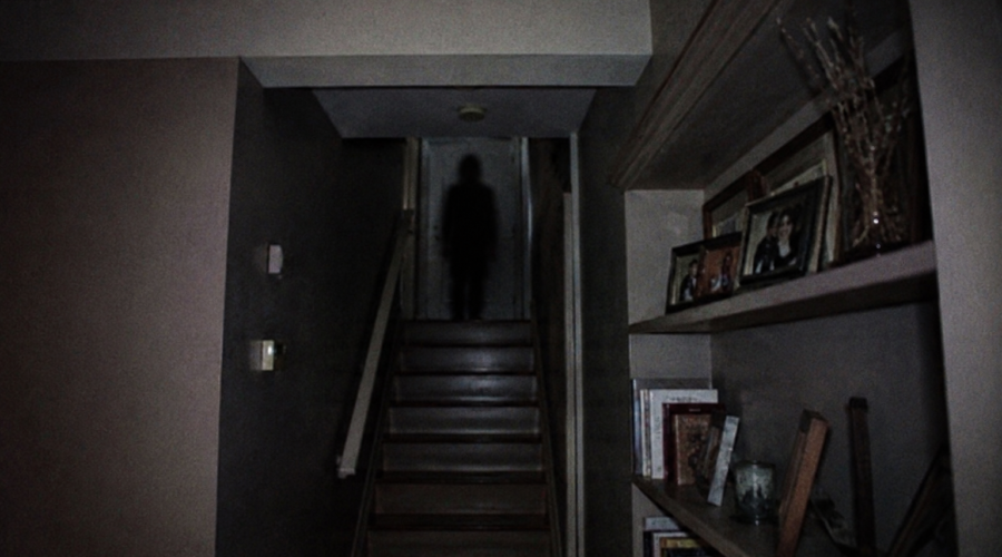 Dark eerie staircase with a shadowy figure at the top, creating a spooky mood.