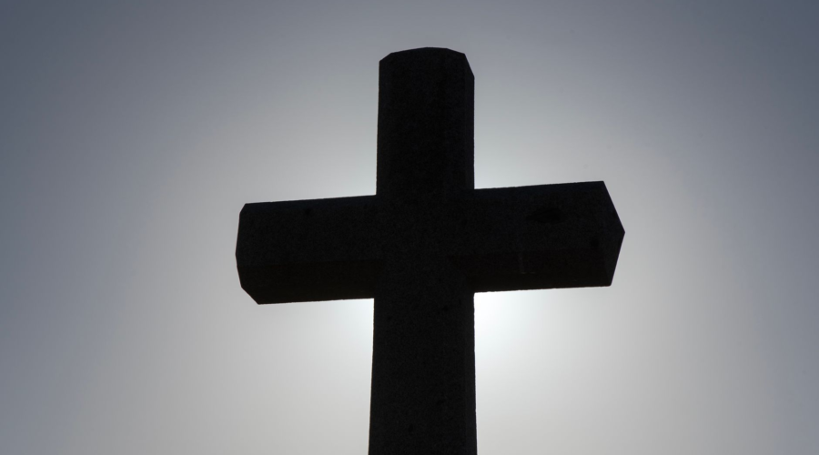 Silhouette of a Christian cross against a bright sky