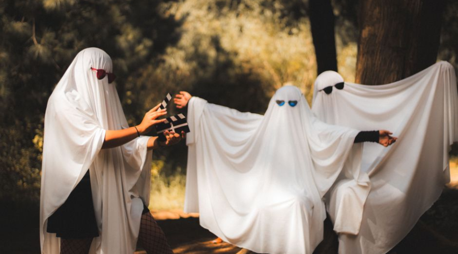 Group of people in playful ghost costumes wearing sunglasses outdoors