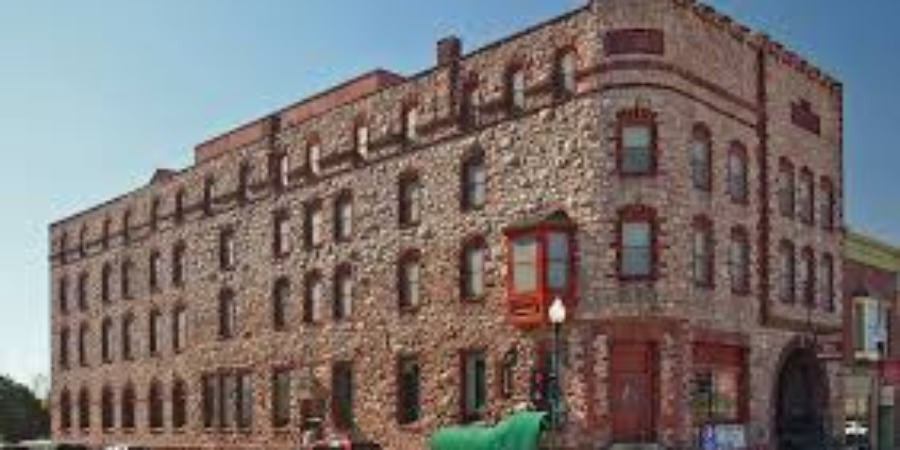 Historic stone building with red-trimmed windows and a canoe displayed outside