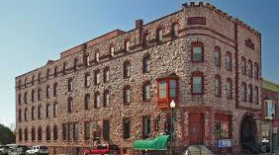 Historic stone building with red-trimmed windows and a canoe displayed outside