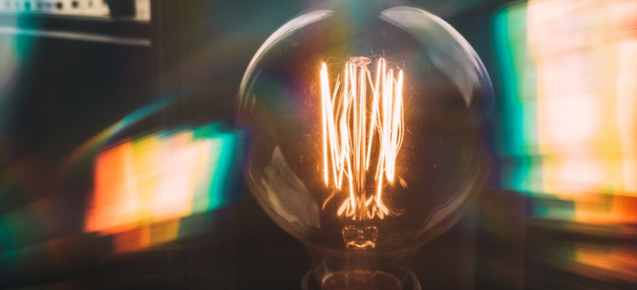 Vintage Edison bulb glowing with colorful reflections in an urban setting