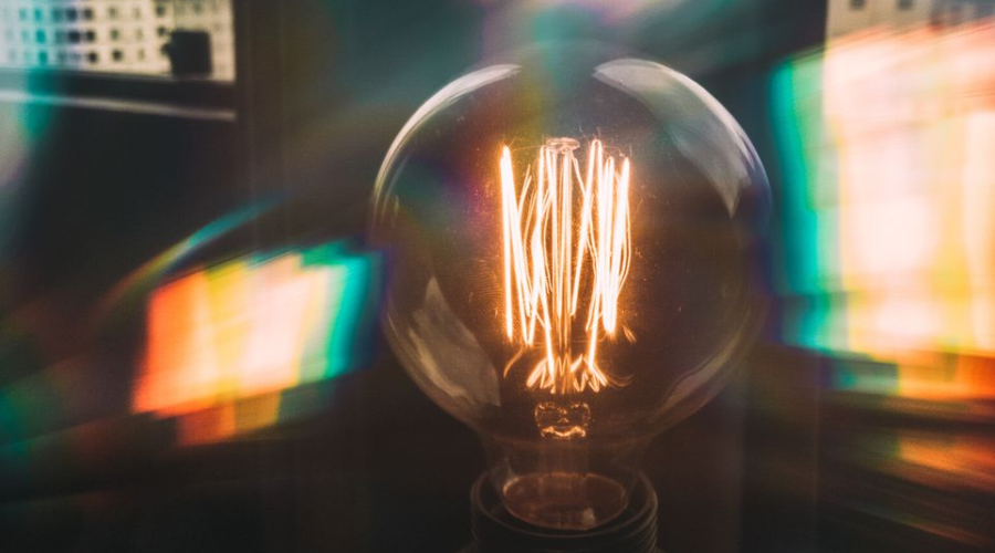 Vintage Edison bulb glowing with colorful reflections in an urban setting