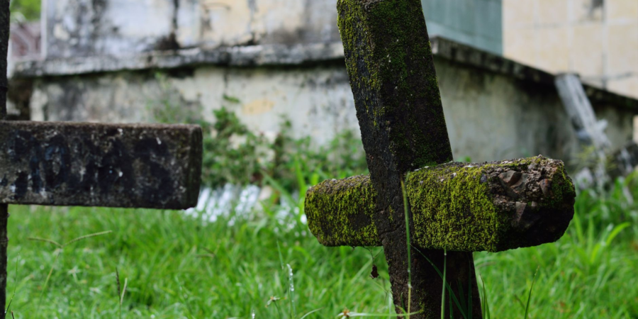 Moss-covered stone crosses in a historic cemetery with weathered tombstones
