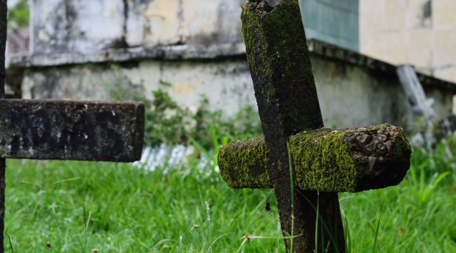 Moss-covered stone crosses in a historic cemetery with weathered tombstones