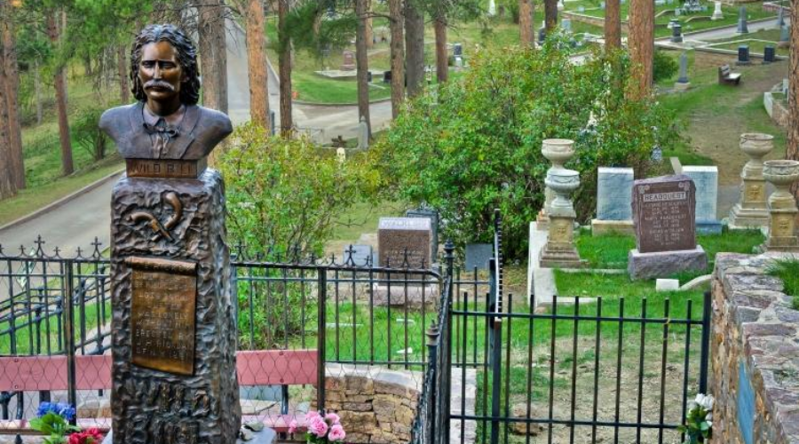Bust statue monument at Mount Moriah Cemetery, surrounded by trees and gravestones.