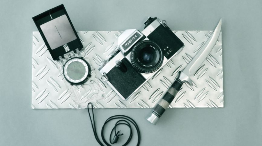 Vintage film camera with flash and knife on a textured metal plate
