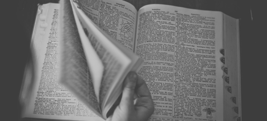 Hand flipping through pages of an open book in black and white