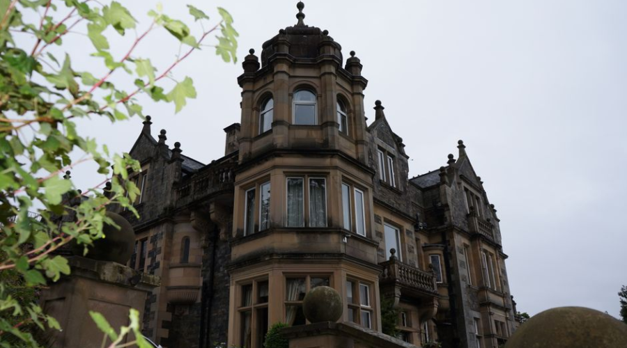 Historic stone mansion with ornate architectural details beneath a cloudy sky
