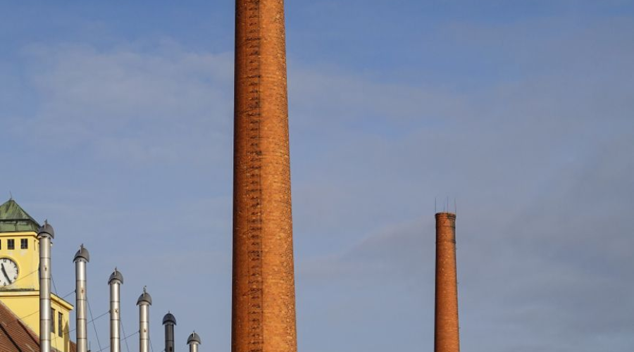 Tall brick chimneys of the Pilsner Urquell brewery under a clear blue sky