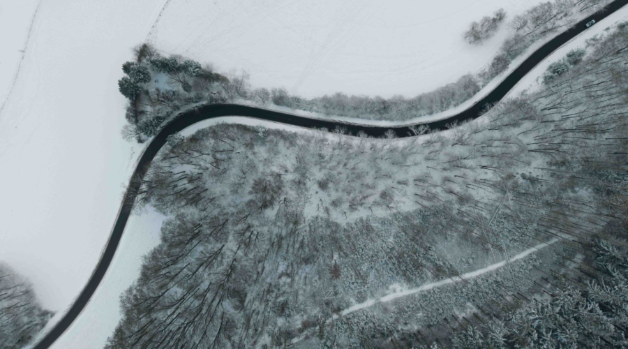 Aerial view of a winding road through a snowy forest