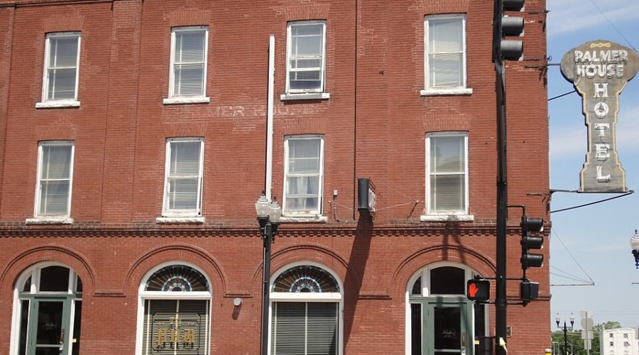 Historic red-brick Palmer House Hotel with arched windows and vintage street sign at Sauk Centre intersection