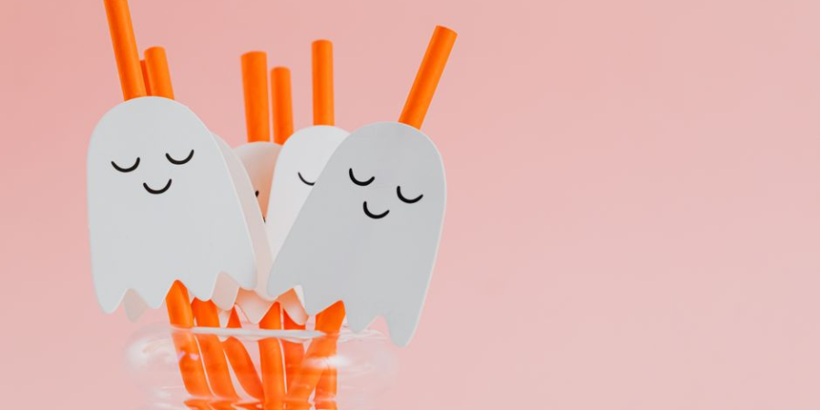 Cute ghost-themed Halloween drink stirrers in a jar on a pink background