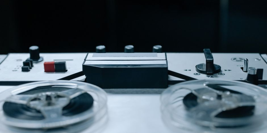 Close-up of a vintage reel-to-reel tape recorder in a dark setting