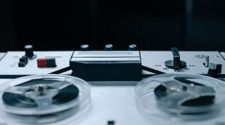 Close-up of a vintage reel-to-reel tape recorder in a dark setting