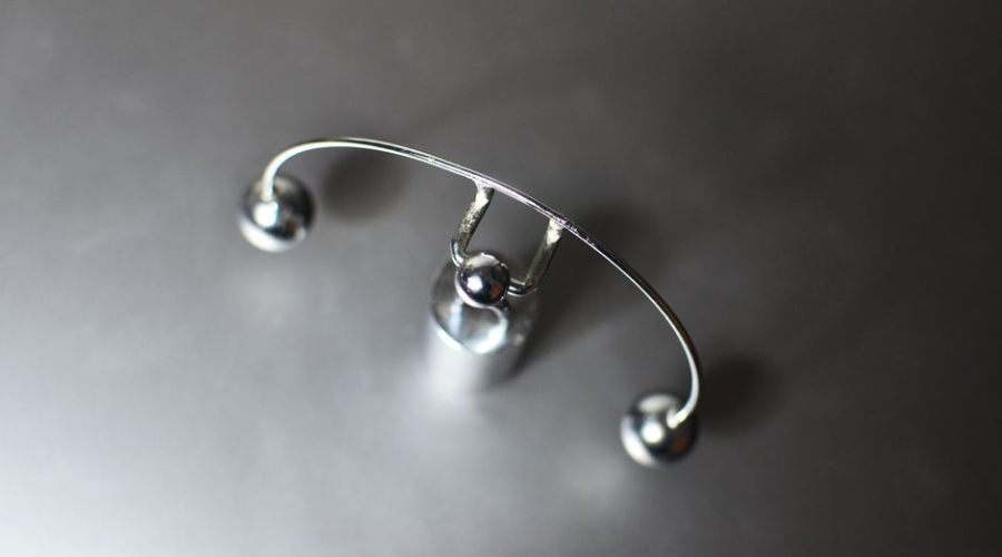 Close-up of a silver curved barbell piercing on a dark surface
