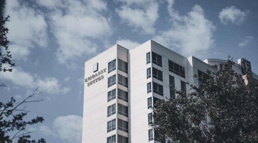Modern white office building with trees under a partly cloudy sky