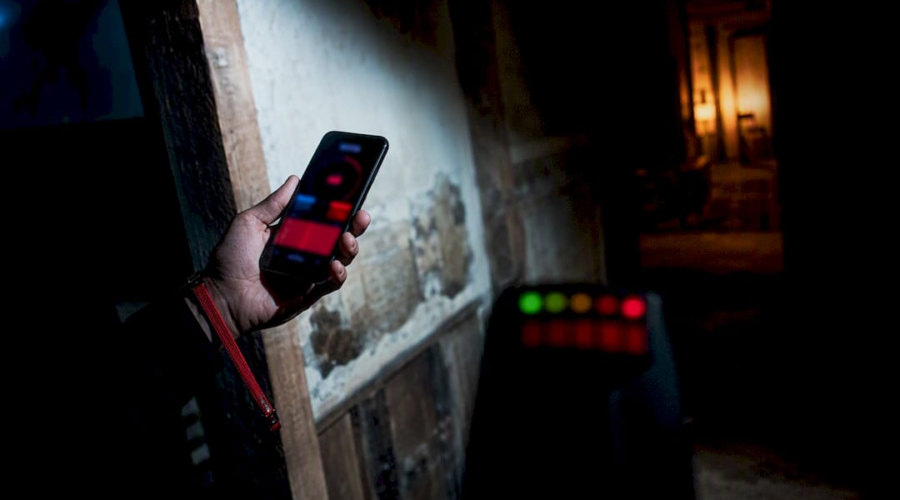Investigator comparing phone app with EMF meter