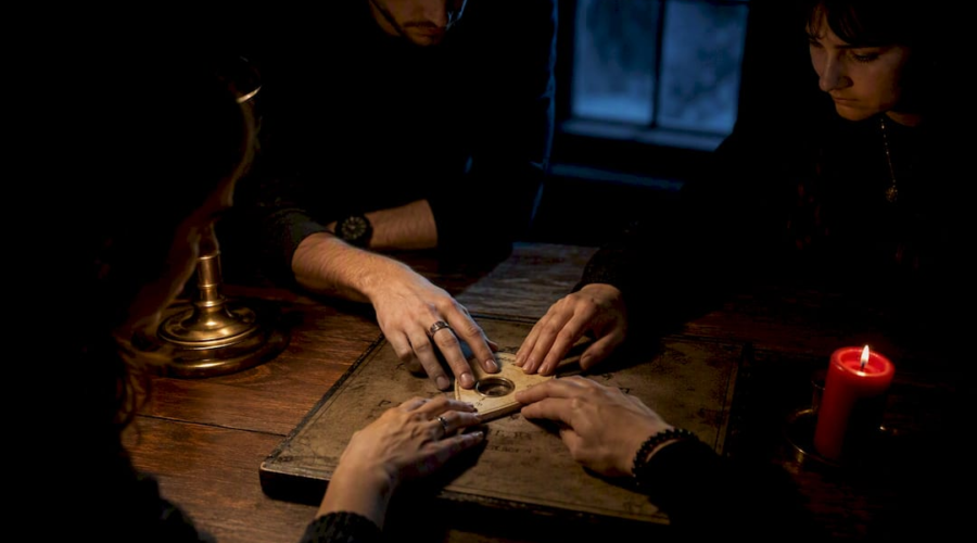 Hands sharing a planchette during Ouija session
