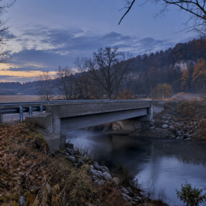 AI-generated conceptual illustration of a rural creek bridge at twilight; not a photograph of the actual location